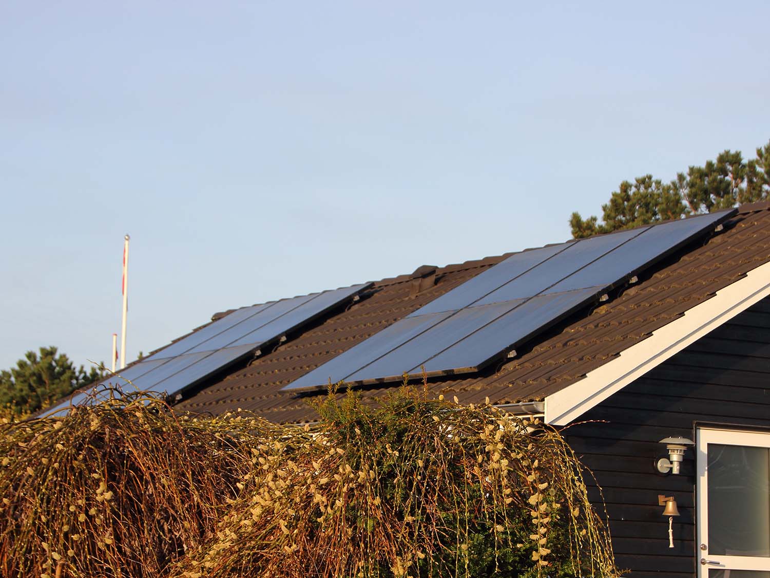 Solceller monterade på taket av ett svart hus